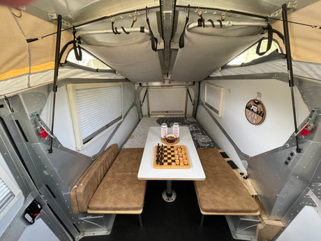 Cozy RV rental interior with a dinette, chessboard, and comfy benches. Perfect for travel!