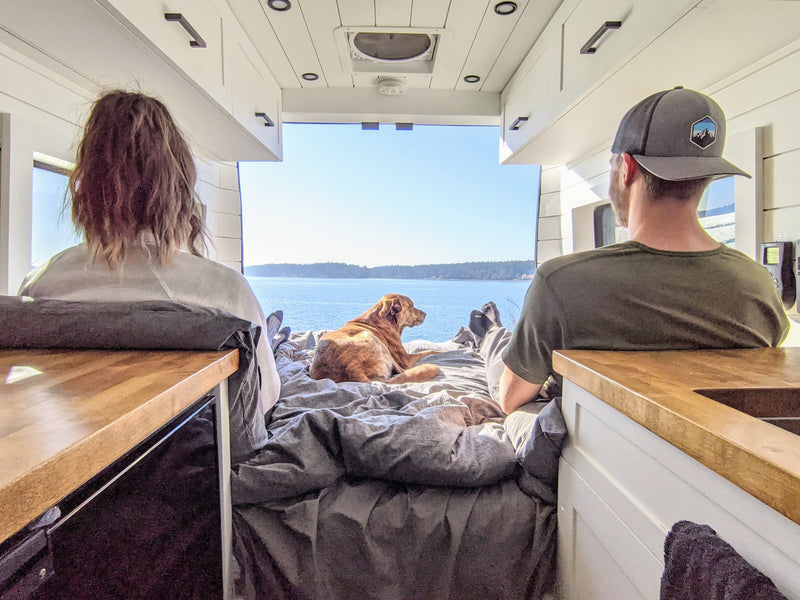 Two people and their dog relax in an RV rental, enjoying the beautiful water view from inside their camper van. — photo 1