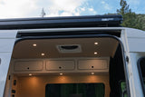 Spacious RV rental camper van interior with ceiling lights, overhead storage, and an exterior Fiamma awning visible.