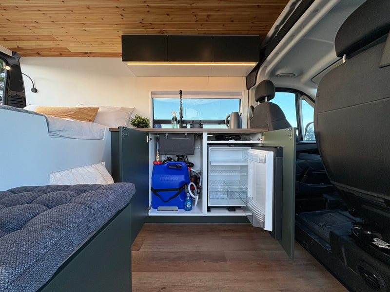 Discover this RV rental's clever interior layout: kitchenette with sink & fridge, cozy bed, and warm wooden ceiling. — photo 12