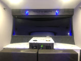 Modern RV rental interior features a compact dining area with a stylish table, comfortable seating, and blue ambient lighting.