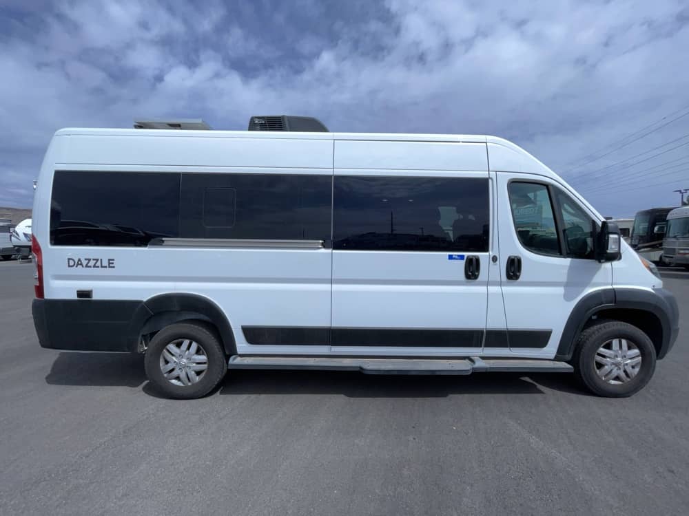 A white Dazzle camper van, perfect for an rv rental, with tinted windows, black trim, and roof-mounted AC.