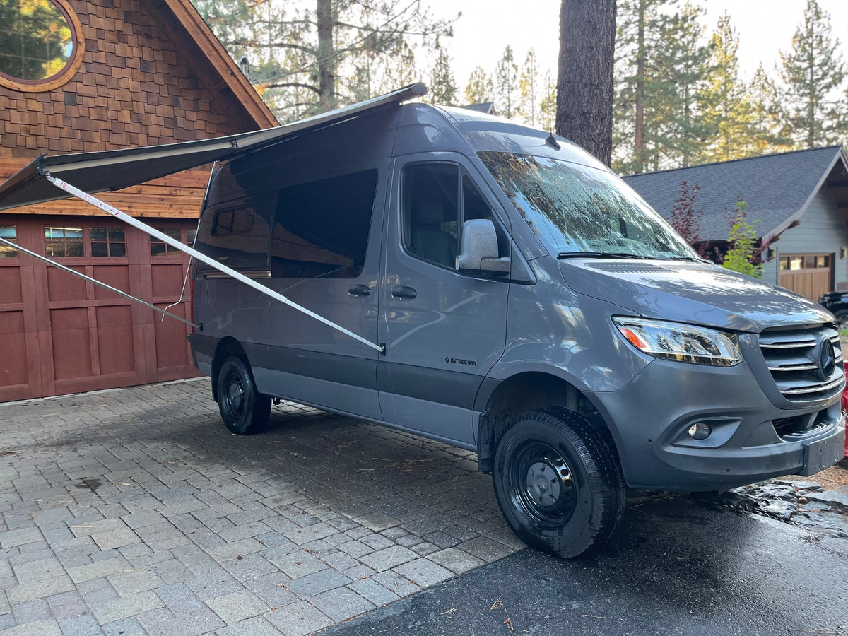  parked on pavers in a wooded area. Perfect for your next outdoor adventure.|Stylish gray Mercedes Sprinter camper van with awning extended — photo 2