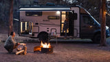 Evening at the campsite with an RV rental: Two people enjoy a campfire next to a Winnebago EKKO motorhome.