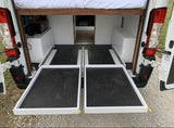 Efficient rv rental storage: Rear pull-out trays in a camper van conversion, with bed above and power system.