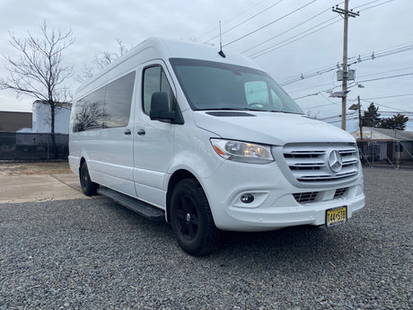 Modern white Mercedes-Benz Sprinter rv rental van with black wheels, parked on gravel in New Jersey, ready for adventure.