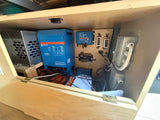 RV rental electrical system: Victron MultiPlus inverter, Orion-Tr Smart DC/DC chargers, & fuse box, all neatly wired in a wood cabinet.