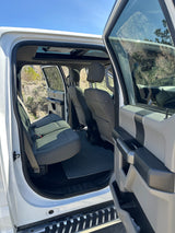 Explore this white pickup truck's roomy rear interior, ideal for your next RV rental journey. Features back seats, open doors, and sunroof.