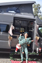 Festive family fun with an RV rental! A woman holds a child upside down in front of a decorated camper van.