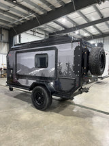 A rugged off-road camper trailer, ideal for rv rental adventures. Features unique mountain graphics and a rear-mounted spare tire.