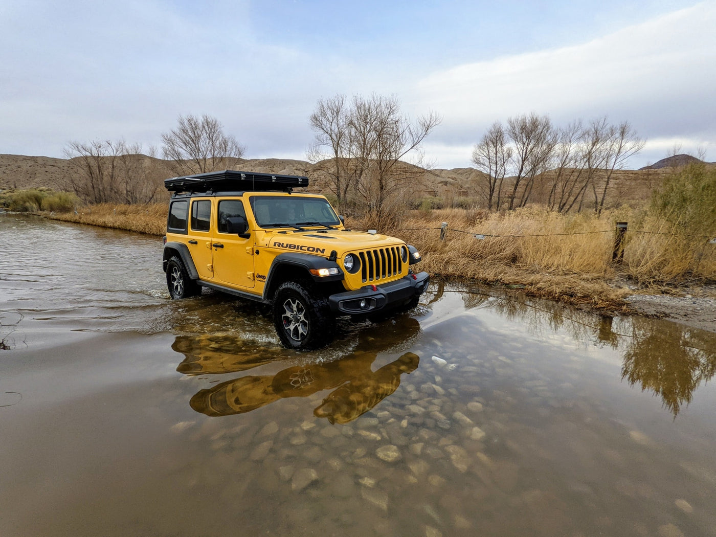  ideal for an RV rental adventure. Mountains and clear skies complete the scene.|Yellow Jeep with rooftop tent on a rugged desert road — photo 16