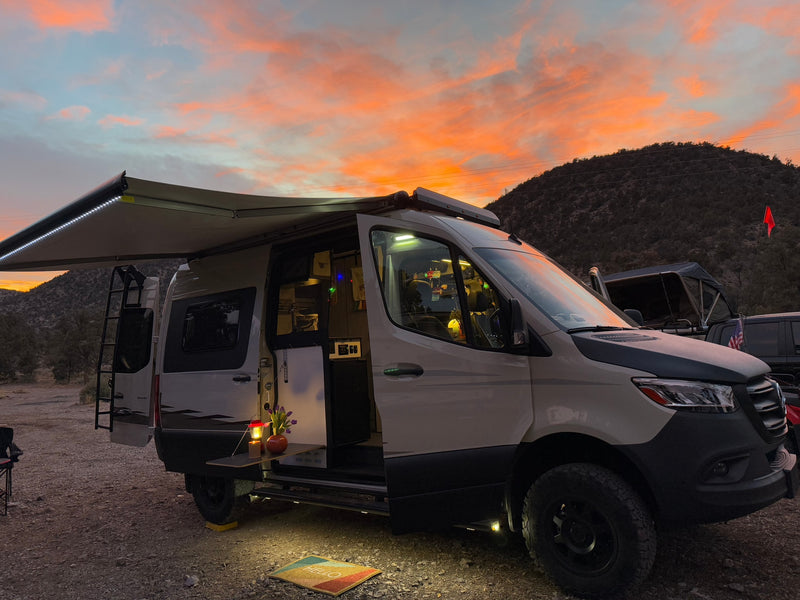 Gorgeous sunset over an RV rental camper van campsite. Awning extended, lights on, revealing a welcoming outdoor setup. — photo 1