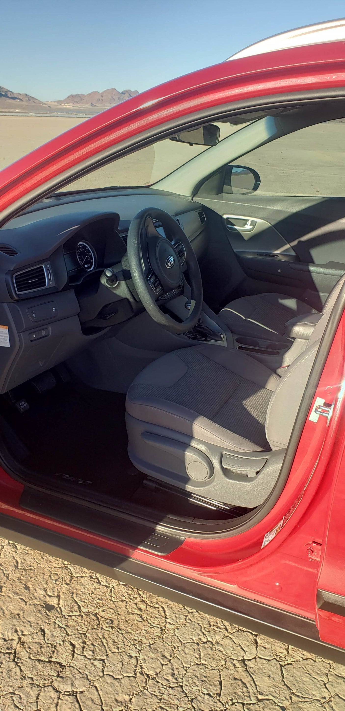 Inside a red car, perfect for a desert road trip, potentially part of an rv rental journey. Mountains in view.
