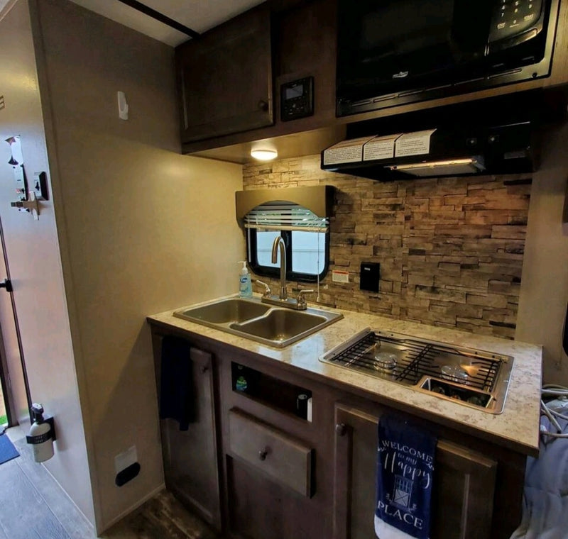 This RV rental's compact kitchen offers a double sink, stovetop, and microwave for on-the-go cooking. — photo 1