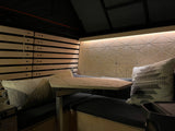 Cozy RV rental interior with patterned wood walls, slatted accents, and a matching table over dark bench seating.