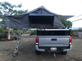 Grey Toyota Tacoma truck with a Nomadic rooftop tent fully deployed, ideal as an rv rental for camping adventures.