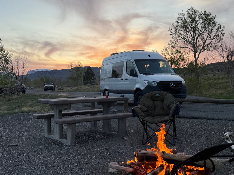 Enjoying the golden hour by a warm campfire at a scenic campsite with a white RV rental van, perfect for outdoor adventures. — photo 3