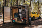 A custom camping trailer, packed with gear like Yeti coolers & Coleman sleeping bags, towed by a Jeep. Ideal for an RV rental alternative.