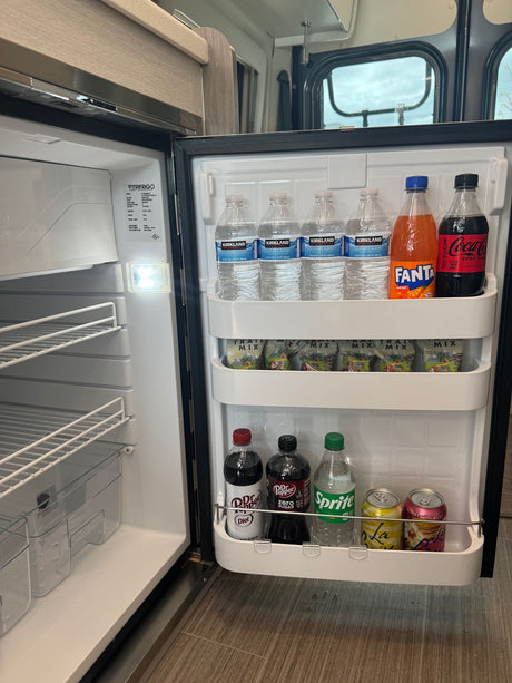 A fully stocked refrigerator in an RV rental, featuring bottled water