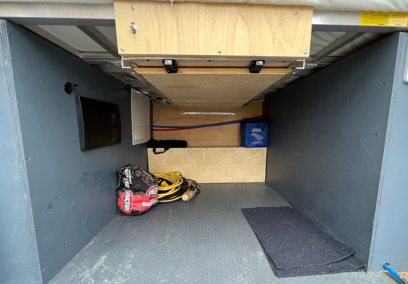 RV rental's underbelly storage with organized power cords, plumbing, and camping supplies. — photo 6