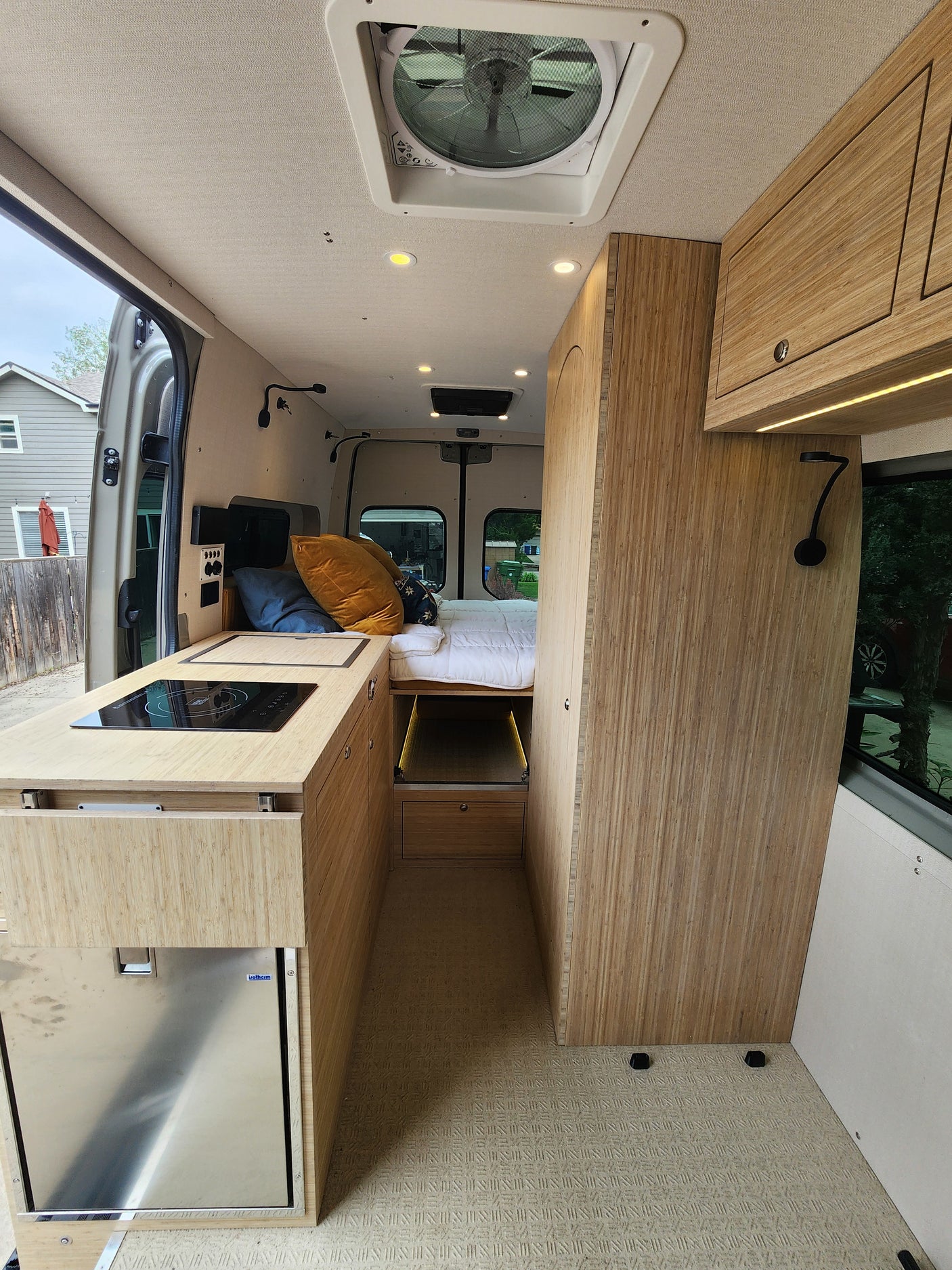 Modern RV rental interior with a spacious kitchenette, comfortable bed, and stylish wood cabinetry. Perfect for mobile living.