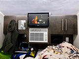 Cozy rv rental interior featuring a textured ceiling, Jensen TV, Haier AC, wood cabinets, and a plush blanket.
