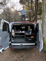 Child enjoys freedom on top of a fully-equipped RV rental camper van, revealing its outdoor kitchen for camping adventures.