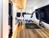 This RV rental showcases a compact camper van interior with a well-equipped kitchen, shower, and comfy seating.