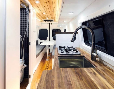 This RV rental showcases a compact camper van interior with a well-equipped kitchen, shower, and comfy seating.