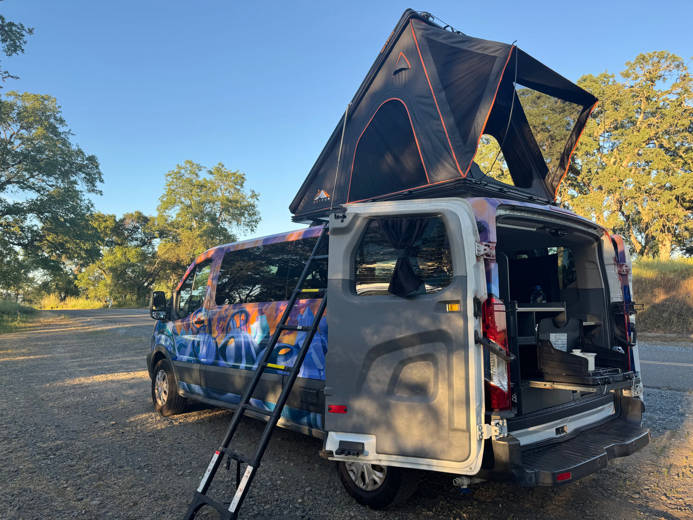 Custom camper van rv rental with pop-up rooftop tent and rear kitchen setup for your next adventure.