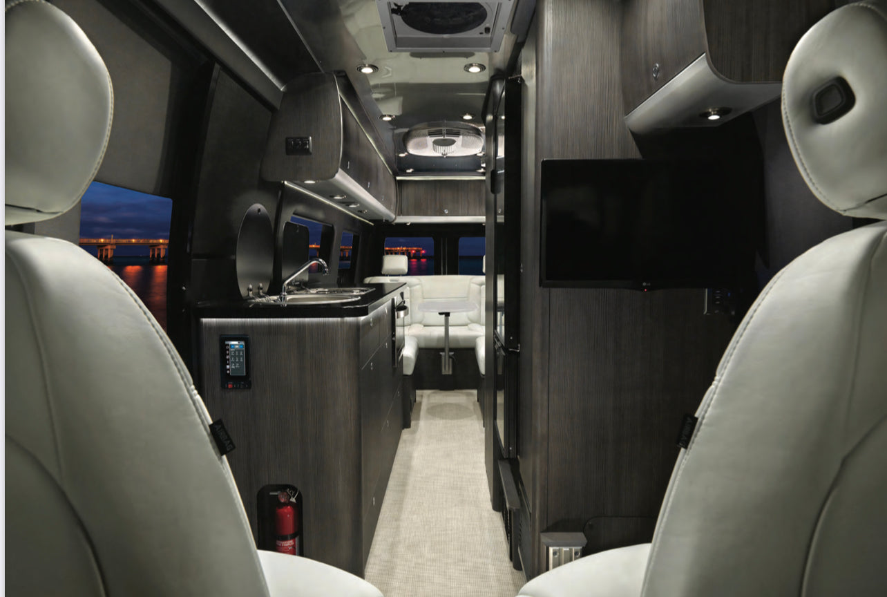 Explore this luxury RV rental's spacious interior with modern kitchen, lounge, TV, and serene window views. Your next adventure awaits!