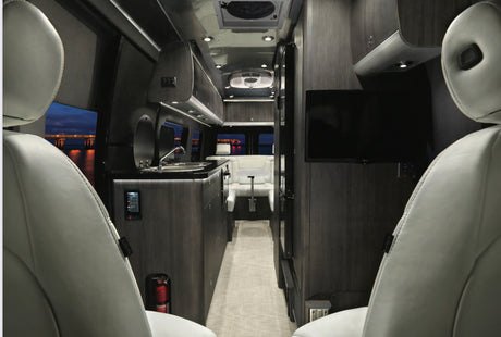 Explore this luxury RV rental's spacious interior with modern kitchen, lounge, TV, and serene window views. Your next adventure awaits!