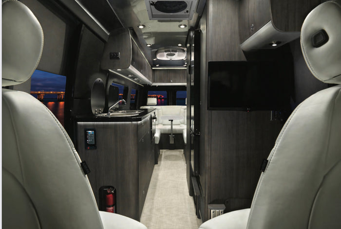 Explore this luxury RV rental's spacious interior with modern kitchen, lounge, TV, and serene window views. Your next adventure awaits!