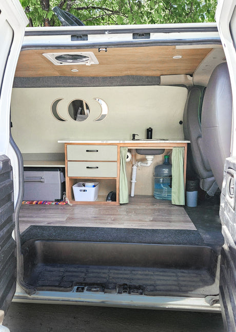 Custom RV rental interior featuring a modern kitchenette, moon phase decor, and compact living space. Perfect for adventure.