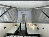 This RV rental shows a pop-up trailer interior: high tent ceiling, two countertop areas, and a central aisle.