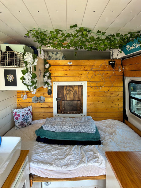 Cozy RV rental bedroom with custom wood paneling, a comfy bed, and green ivy decor for a relaxing stay.