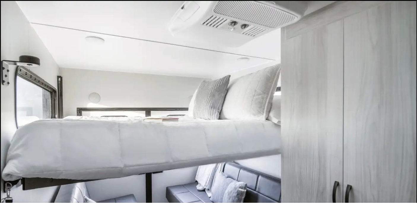 Compact RV rental interior featuring a clever drop-down bed, comfy lower seating, and built-in storage.