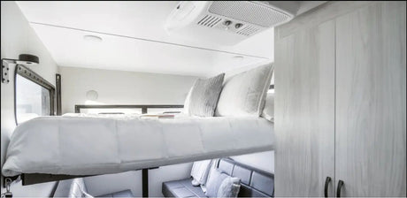 Compact RV rental interior featuring a clever drop-down bed, comfy lower seating, and built-in storage.