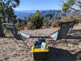 Scenic RV rental campsite features two chairs, coffee setup, and vast canyon views. Ideal outdoor relaxation.