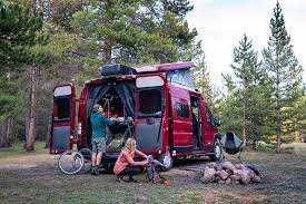  flanked by a quilted bench and a swiveled passenger seat.|Adventure awaits! This red RV rental is parked in a scenic desert landscape with mesas and a blue sky — photo 11