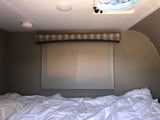 Cozy RV rental bedroom interior with rumpled bed, window shade, and ceiling vent. Ready for adventure.
