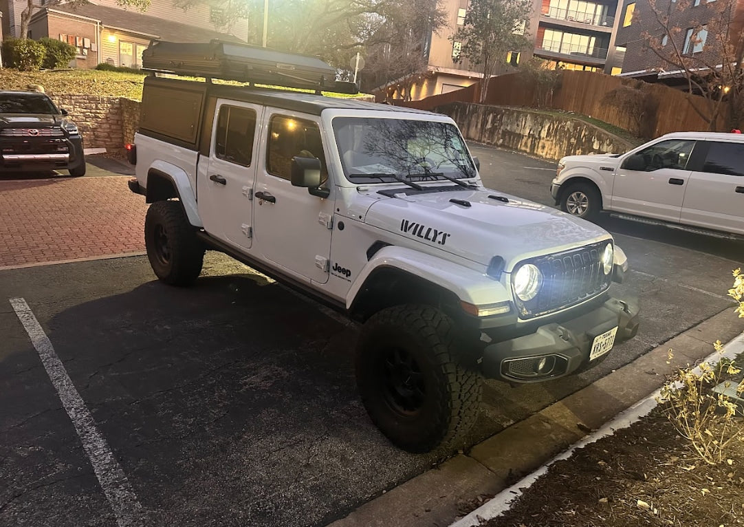 A robust white Jeep Gladiator with a rooftop tent, ideal for an rv rental for off-road camping and adventure travel.