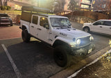 A robust white Jeep Gladiator with a rooftop tent, ideal for an rv rental for off-road camping and adventure travel.