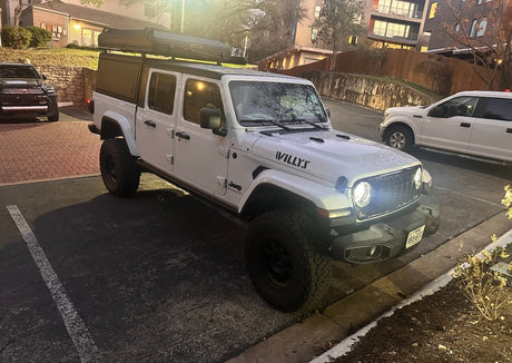A robust white Jeep Gladiator with a rooftop tent, ideal for an rv rental for off-road camping and adventure travel.