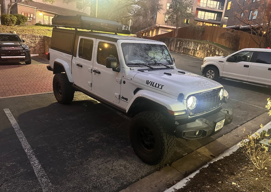 A robust white Jeep Gladiator with a rooftop tent, ideal for an rv rental for off-road camping and adventure travel.