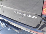 Rear of a dark Ultimate Coach RV, ideal for an RV rental. Features a tow hitch and bumper sensors.