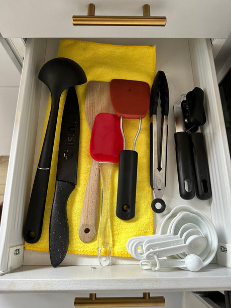 RV rental kitchen drawer organized with essential utensils: ladle, knife, spatulas, tongs, can opener, measuring cups.