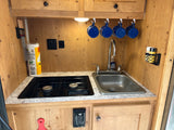 Well-equipped RV rental kitchen featuring a stove, sink, and various amenities.