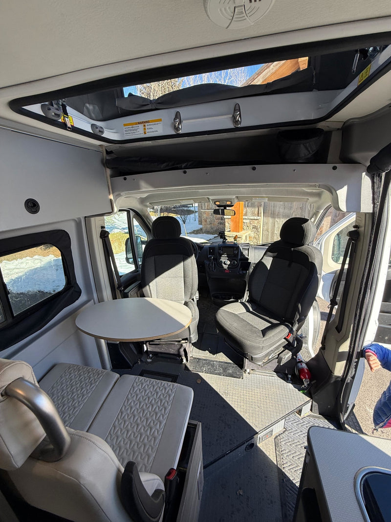 Inside this bright rv rental camper van, view of the cockpit, dining table, and living area. Features a pop-top roof. — photo 12