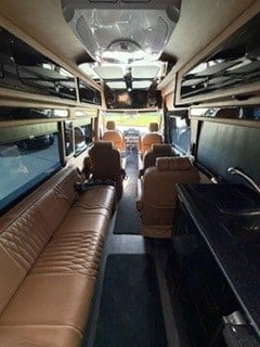  and a screen in the aisle.|Modern RV rental: Dark camper van interior with a narrow aisle — photo 4